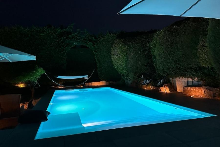 Pool, der blau beleuchtet ist bei Nacht.