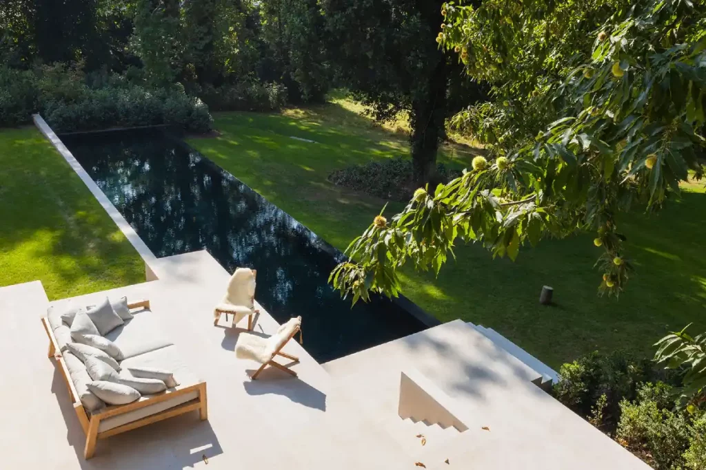 Helle Terrasse mit Liegestühlen und dunklem Infinity-Pool
