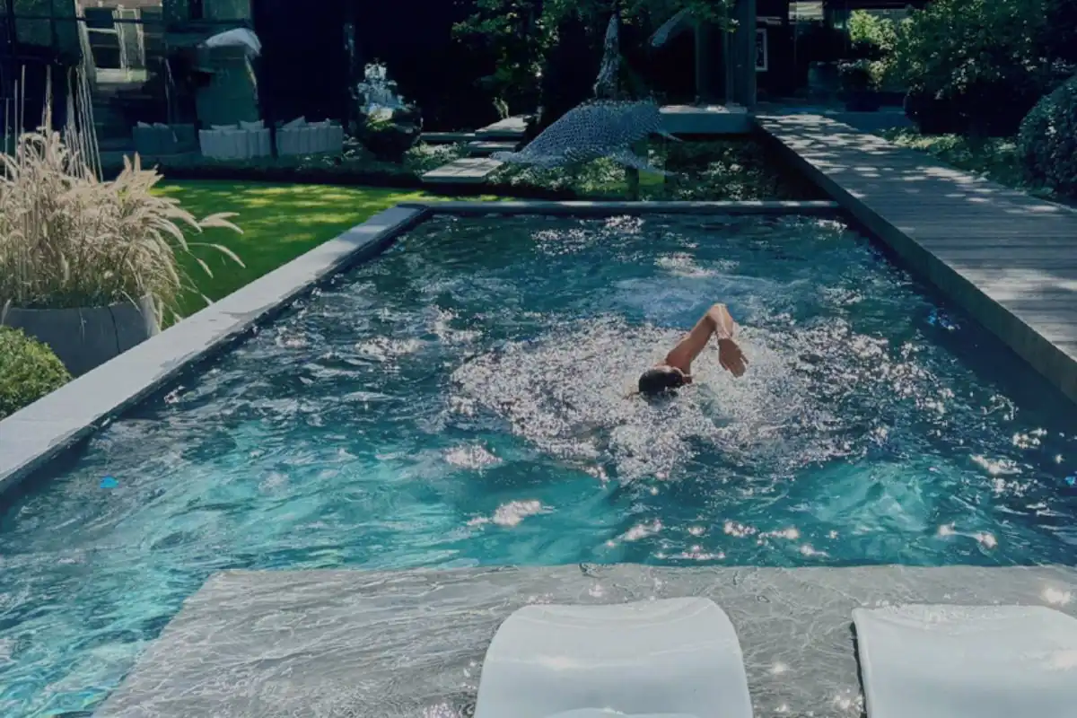 Mann mit Schwimmhaube, der im Pool mit Gegenstromanlage schwimmt